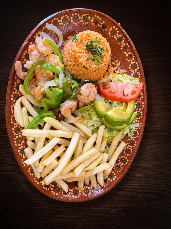 Shrimp with green pepper and onion, a mound of rice, french fries, lettuce, tomato and avocado.