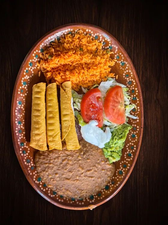 Three crisp rolled tortillas with rice, refried beans, lettuce, tomato, sour cream and guacamole.