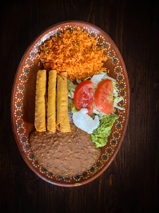 A second view: three crisp rolled tortillas with rice, refried beans, lettuce, tomato, sour cream and guacamole.