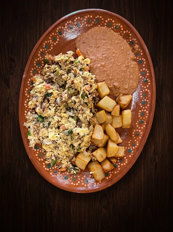 A second view: shredded dried beef scrambled with egg, beside fried potato cubes and refried beans.
