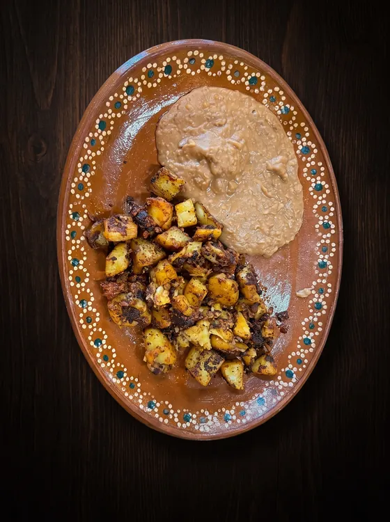 Potato cubes fried with chorizo until crisp, beside smooth refried beans.