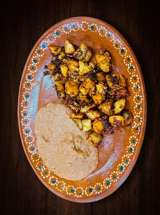 A second view: potato cubes fried with chorizo beside smooth refried beans.