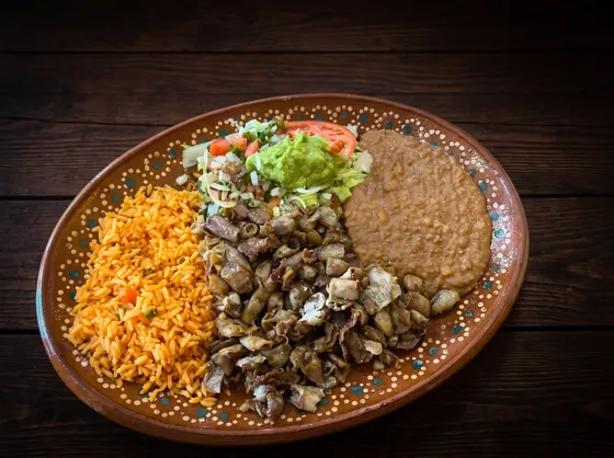 Small crisp-fried pieces of meat between rice and refried beans, with lettuce, guacamole and tomato.