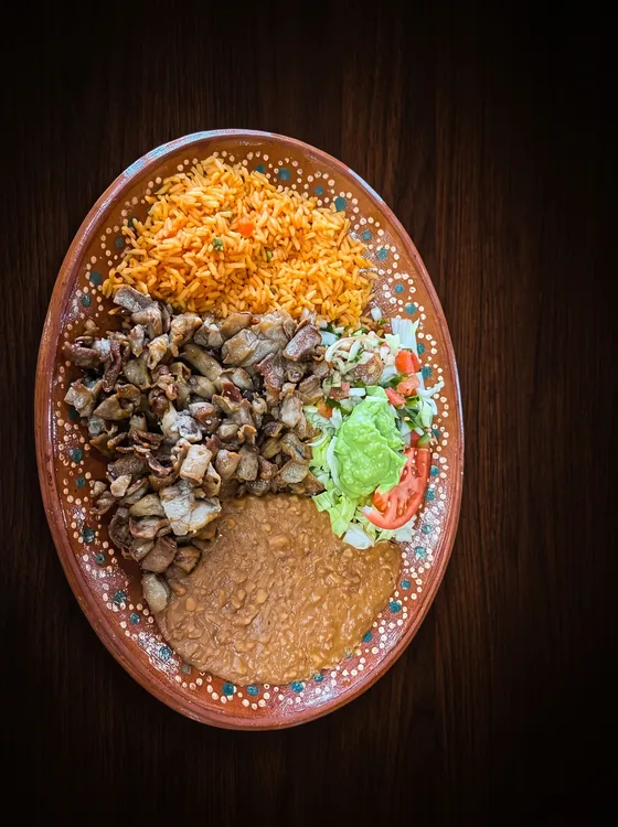 A third plate of small crisp-fried pieces of meat, with rice, refried beans, guacamole and lettuce.
