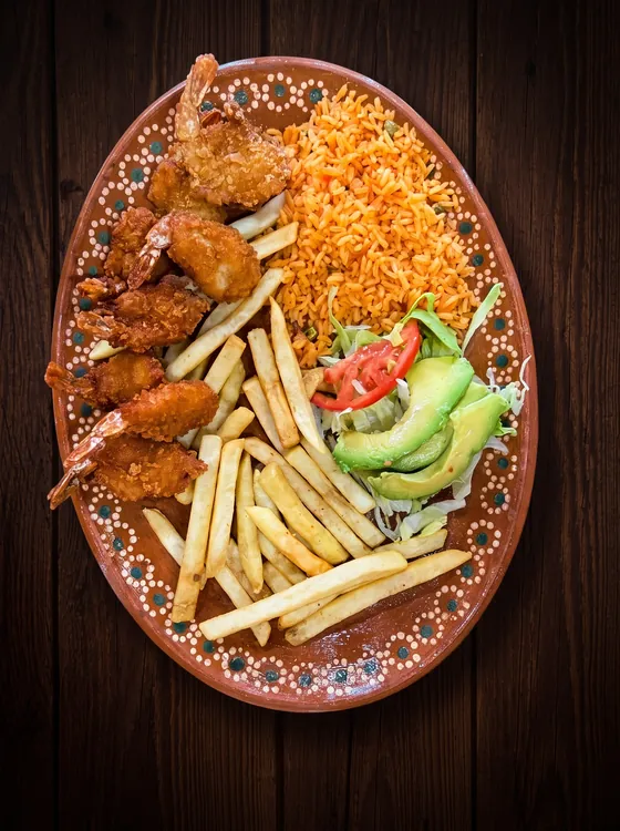 Breaded shrimp with their tails on, french fries, rice, sliced avocado, lettuce and tomato.