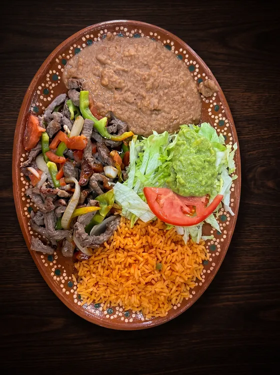 Grilled beef strips with red and green peppers and onion, with refried beans, lettuce, guacamole, tomato and rice.