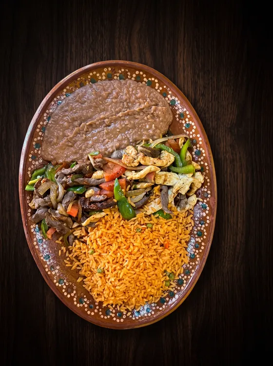 Grilled chicken and beef strips with peppers and onion, between refried beans and rice.