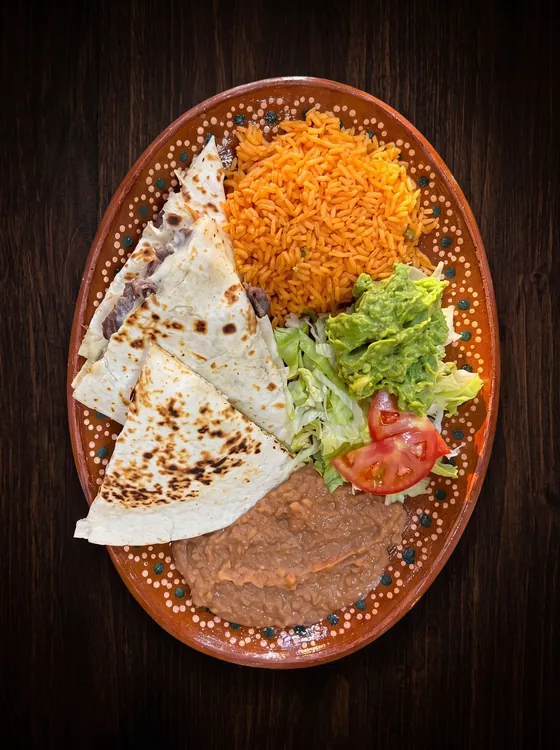 Toasted flour tortilla wedges filled with cheese, with rice, guacamole, lettuce, tomato and refried beans.
