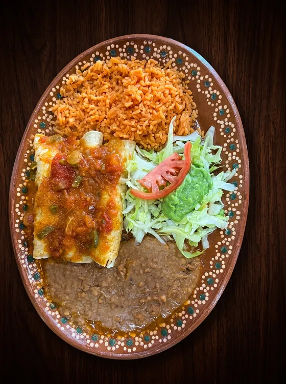 Enchiladas under chunky red sauce with rice, refried beans, lettuce, guacamole and tomato.