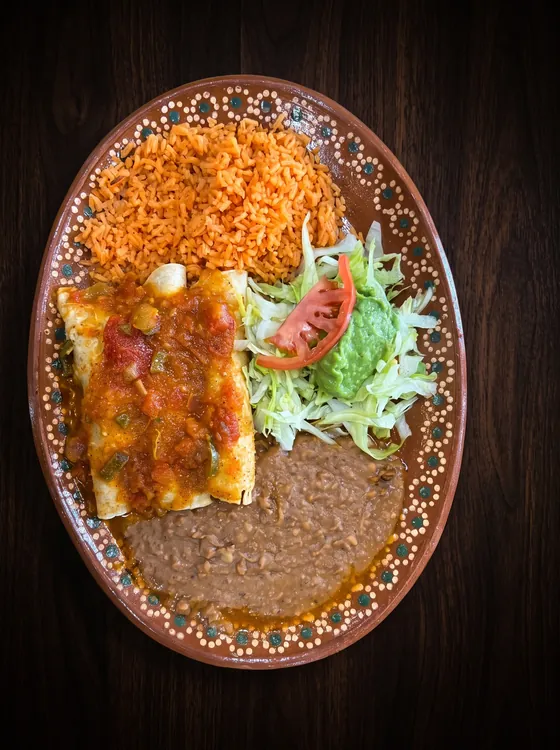 A second view: enchiladas under chunky red sauce with rice, refried beans, guacamole and tomato.