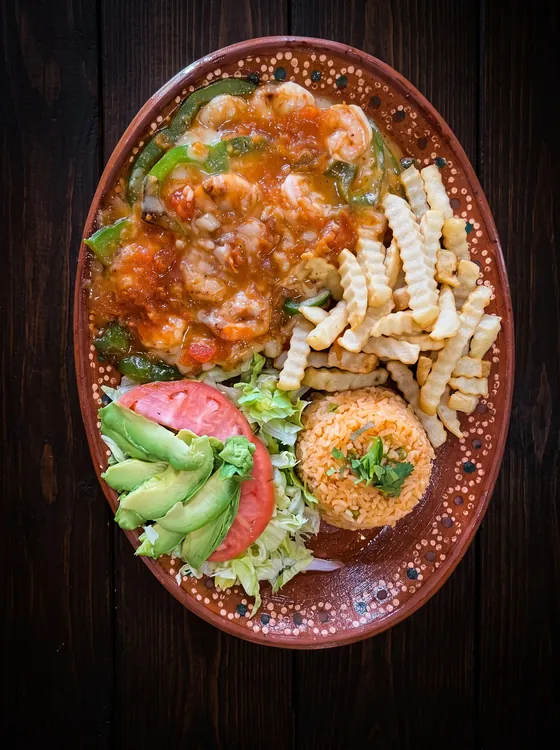 Shrimp under red sauce and melted cheese with peppers, crinkle-cut fries, rice, sliced avocado, lettuce and tomato.